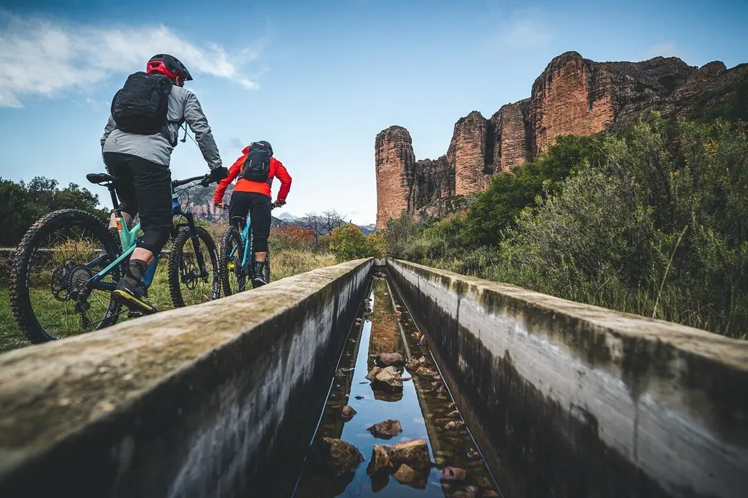 Dos 'biker' en direcci&oacute;n a Riglos con los emblem&aacute;ticos Mallos al fondo de la imagen. Foto: Nacho Trueba