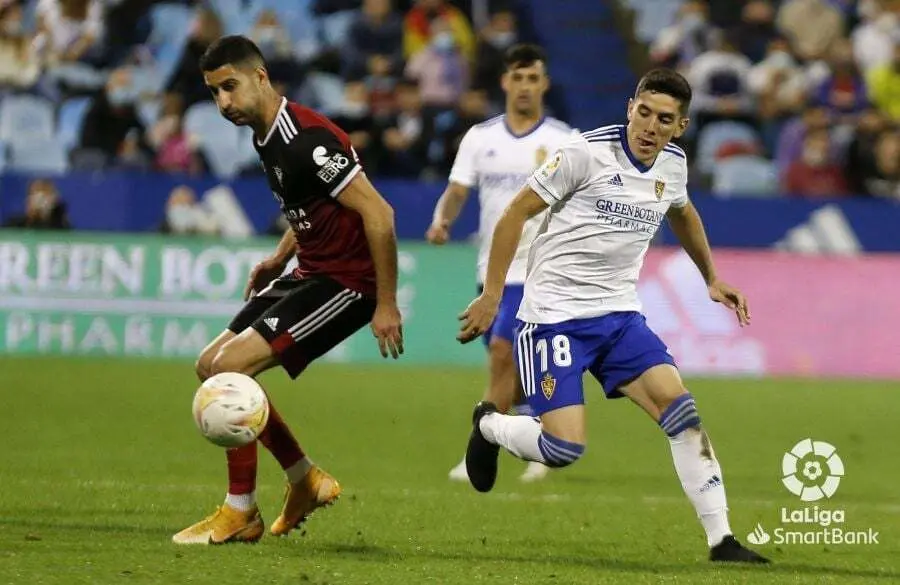 Fran G&aacute;mez pelea un bal&oacute;n en la banda de La Romareda. Al fondo, Nano Mesa vigila la jugada | Foto: La Liga