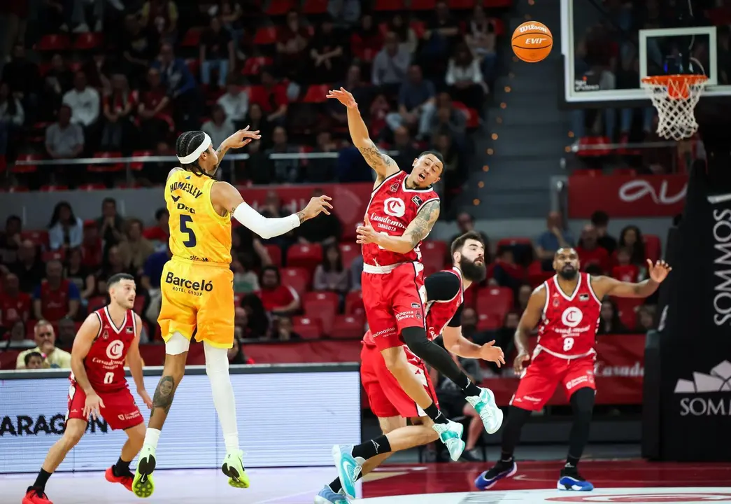 Homesley hace un pase ante Slaughter, que intenta taponar. Fotograf&iacute;a: ACB Photo.