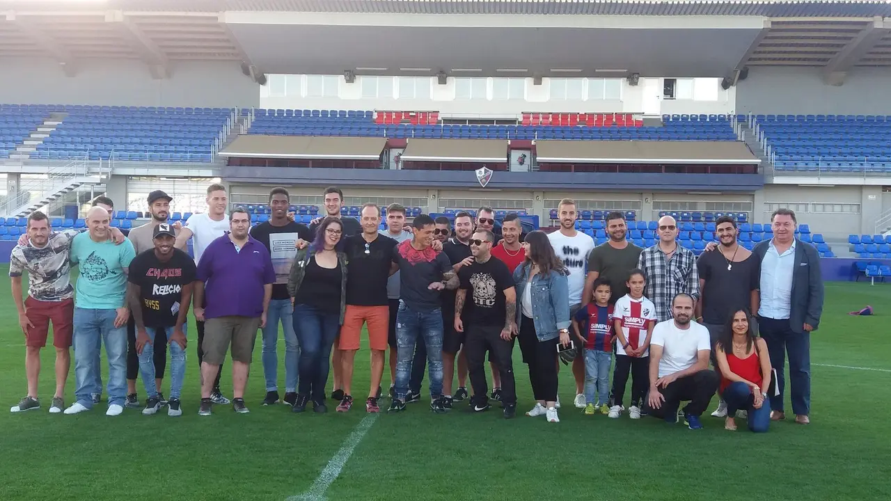 Imagen de familia sobre el c&eacute;sped de El Alcoraz de los tatuados con jugadores, el autor de los tatus y el presidente del Huesca. Foto: Sporthuesca 