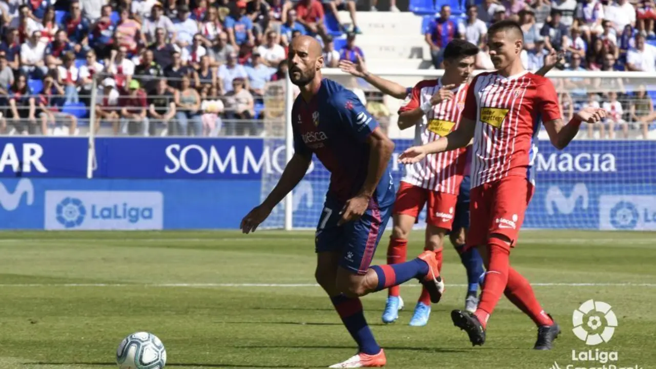 Rico se lleva el bal&oacute;n ante dos jugadores del Sporting de Gij&oacute;n. Foto: LFP