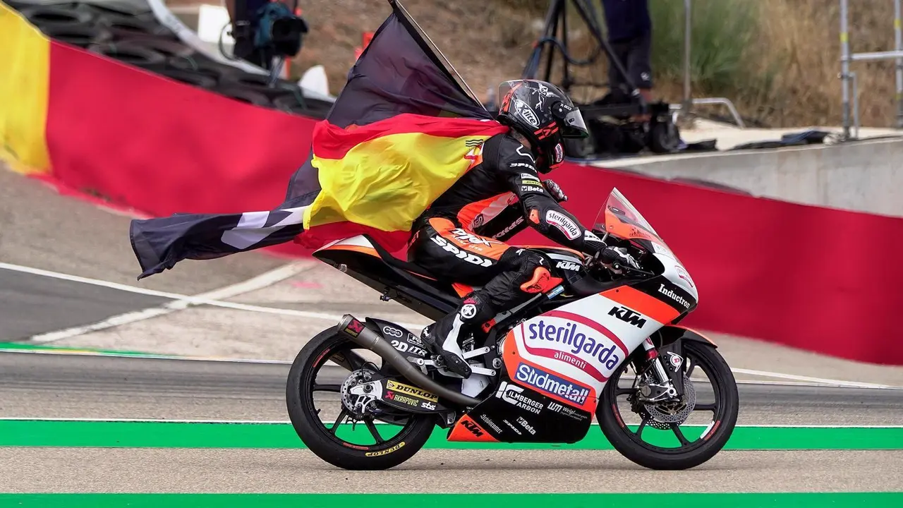 El espa&ntilde;ol Ar&oacute;n Canet (KTM) porta una bandera de Espa&ntilde;a tras adjudicarse la victoria en el Gran Premio de Arag&oacute;n de Moto3 que se ha disputado en el circuito Motorland de Alca&ntilde;iz. | Foto: EFE/Antonio Garc&iacute;a