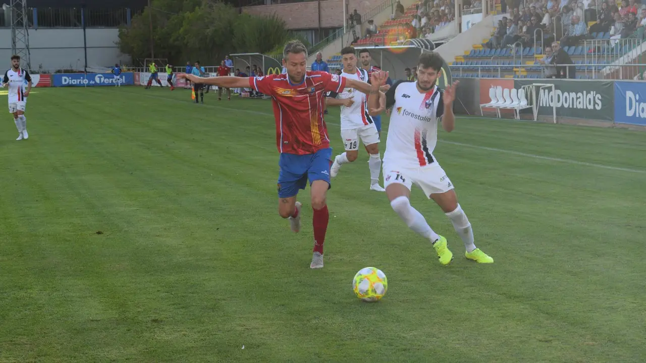 Bravo pelea un bal&oacute;n con To&ntilde;o en el partido entre el CD Teruel y el Villanueva CF | Foto: Isabel Traver