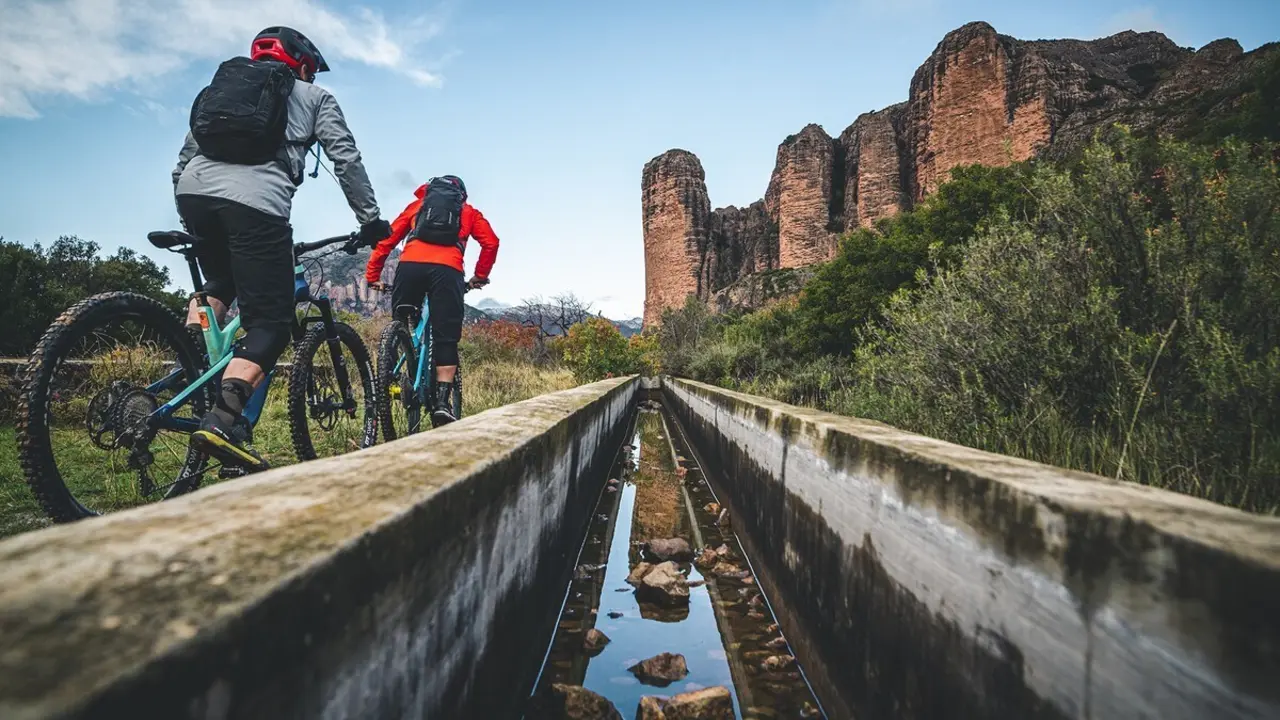 Dos 'biker' en direcci&oacute;n a Riglos con los emblem&aacute;ticos Mallos al fondo de la imagen. Foto: Nacho Trueba