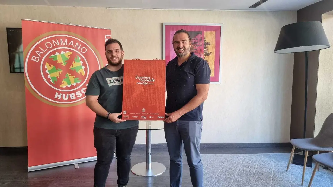Adri&aacute;n Lera y N&eacute;stor Oliva sostienen el cartel de la campa&ntilde;a de socios del BM Huesca 2023/24. Foto: BM Huesca