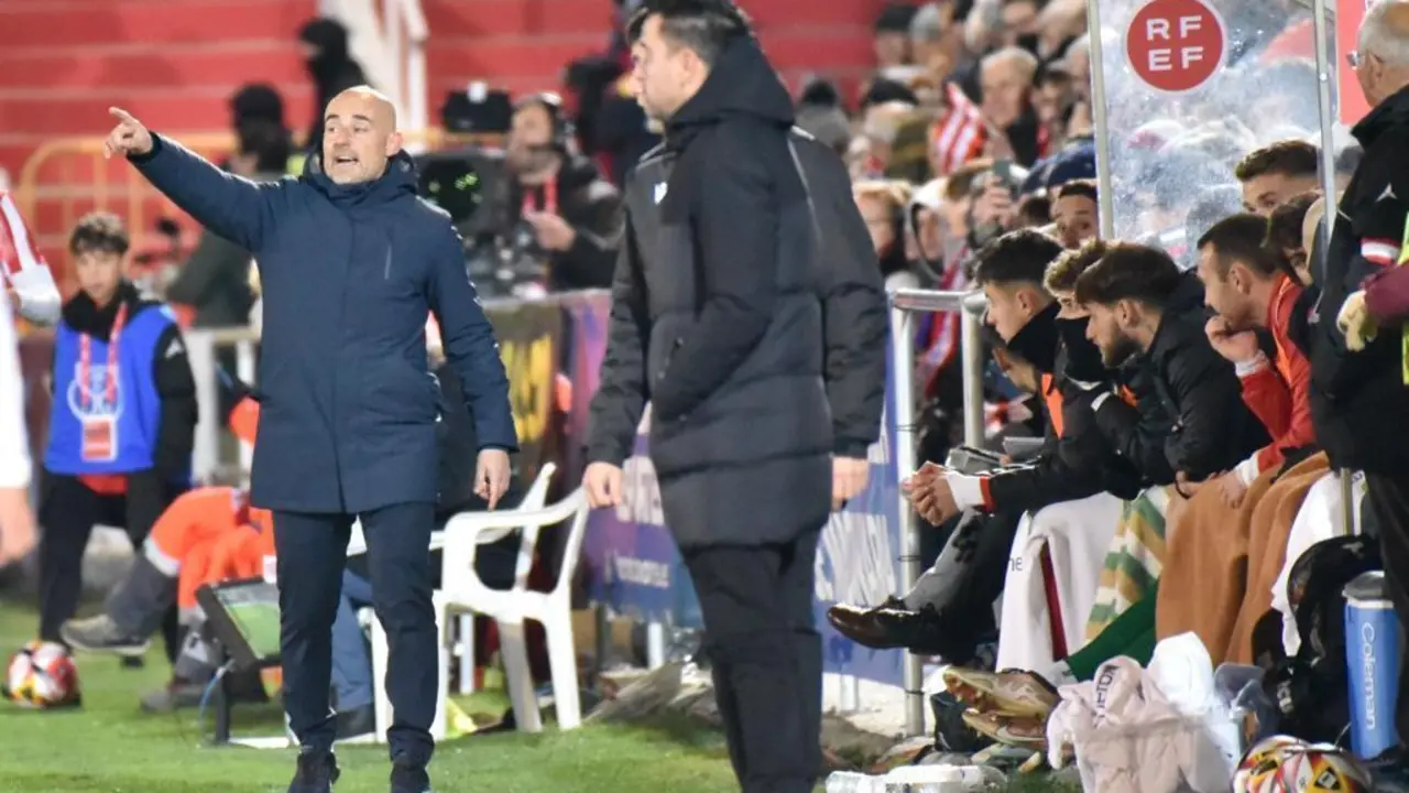 Dani Mart&iacute;nez, al fondo de la imagen, da &oacute;rdenes a sus jugadores con Xavi, atento a lo que sucede en el Barbastro-Bar&ccedil;a de Copa del Rey. Foto: C.Pascual