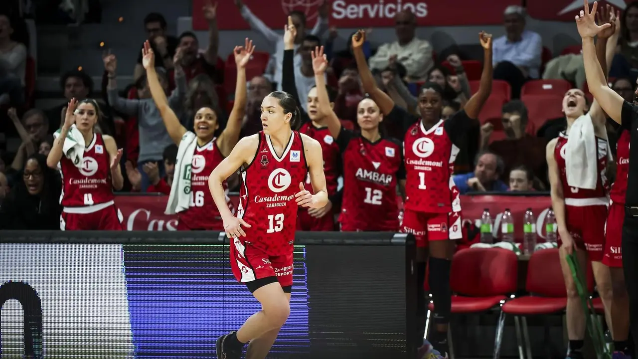 Helena Pueyo anota un triple mientras el banquillo del Casademont lo celebra. Fotograf&iacute;a: Casademont Zaragoza.