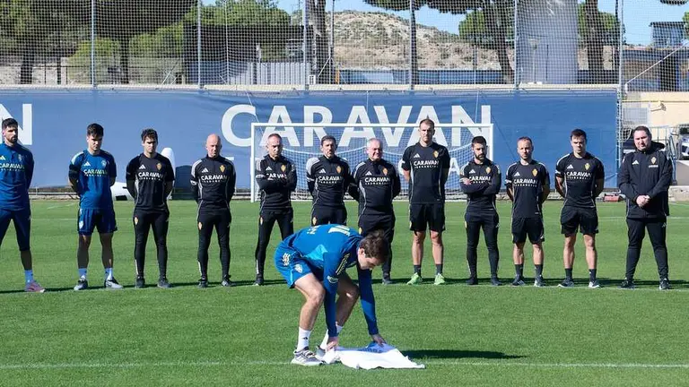 Francho Serrano colocando una camiseta del Real Zaragoza con el nombre de "Jorge" sobre el c&eacute;sped de la Ciudad Deportiva / RZ