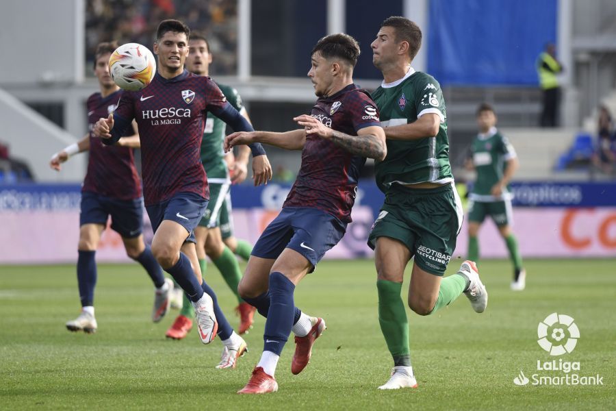 Ratiu, en el Huesca - Almería, protege el balón ante un jugador visitante.